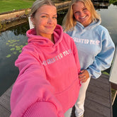 Two people wearing matching 'CREATED ME' hoodies by a body of water.